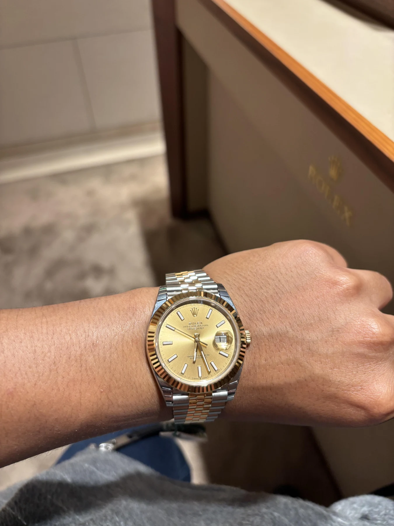 Two-tone Rolex watch with a gold dial worn on a wrist